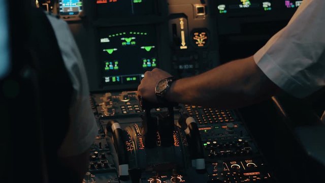 Close shot of cabin interior of Airbus A319 A320 A321. Flight deck and pedestal. Thrust and thrust reverse control levers with co-pilot's hand in white shirt