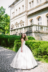 Obraz premium Elegant bride in luxurious ivory dress stands on path along gree
