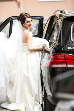 Beautiful bride sits down in black Mercedes GLE