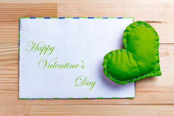 Green heart on natural wooden table on Valentine's Day.