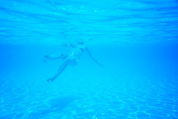 woman swimming in the pool view from under a water