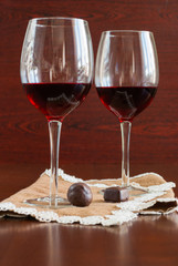 Two glasses of wine on a wooden table. Candies.