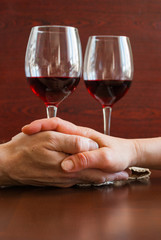 Two glasses of wine on a wooden table.  Hands.