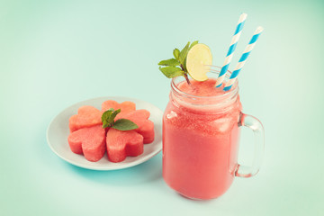 Watermelon smoothie in Mason jar decorated with lime, mint, straws