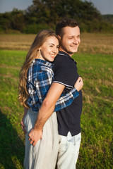 amorous and pleased couple cuddling in a field