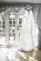 white Wedding dress hanging from a curtain pole