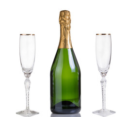 Unopened bottle of champagne and drinking glasses on white 