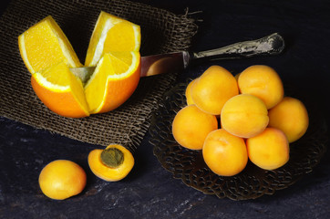 Delicious fresh apricots placed  in copper plate with fresh orange on dark background.Top view,Close up..