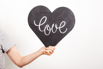 hand holding blackboard in the shape of heart with text love