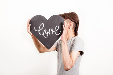 young man holding blackboard in the shape of heart.