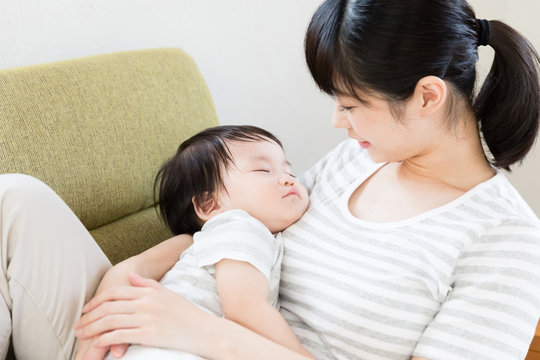 asian mother and baby relaxing on the sofa