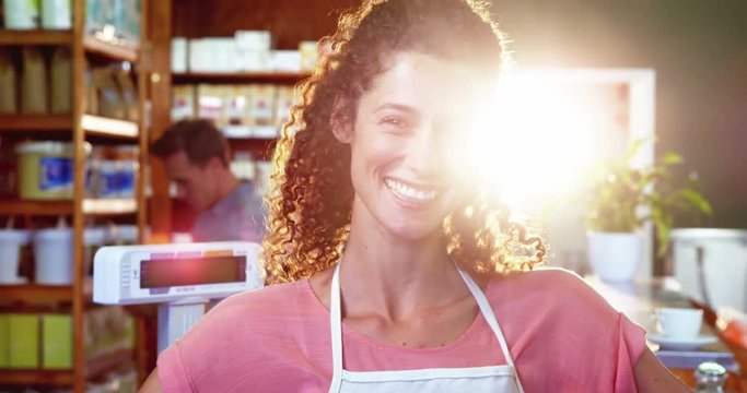 Portrait of smiling female staff standing with hands on hip in grocery section of supermarket 4k