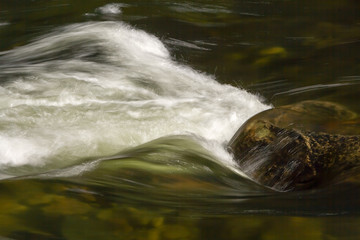 Flowing water around a rock at Merced River in Yosemite Nat'l Park, CA, USA