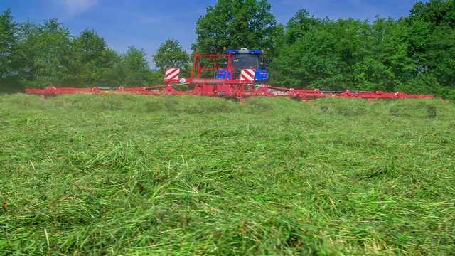 We Can See That A Huge Machinery Is Turning Hay Around. It Is Summer Time Where There Is A Lot Of Work To Do On The Fields.
