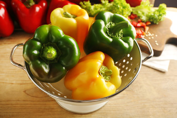 Sweet yellow and green peppers in colander on kitchen table