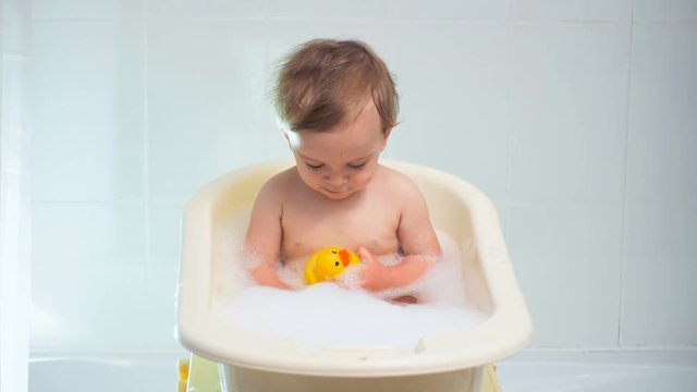 4K footage of cute baby boy playing with rubber duck in bath