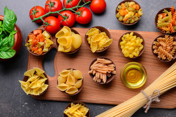 Different kinds of pasta in bowls on color background