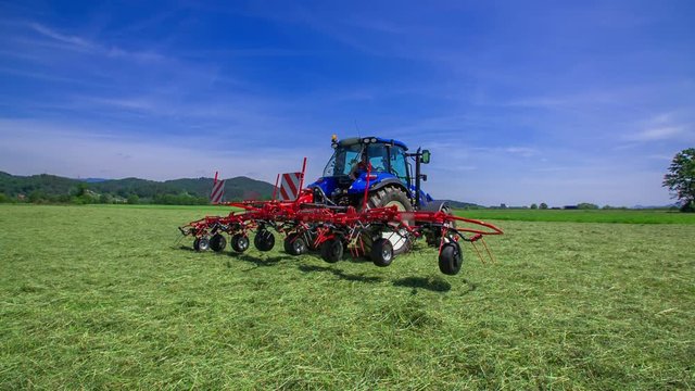 One side of the rotary rakes machinery is opening and a farmer will be able to start preparing hay in the fields.
