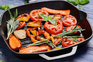 Iron cast pan with grilled vegetables and herbs, closeup