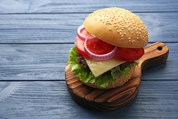 Delicious cheeseburger on wooden background