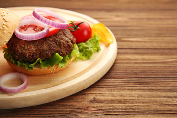 Delicious burger on wooden background, closeup