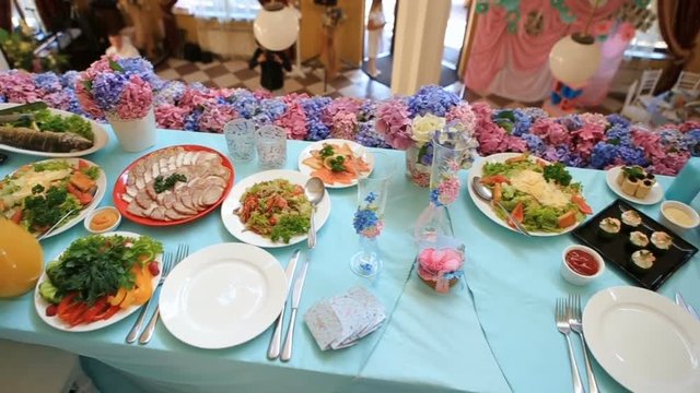 Many dishes served on blue dinner table prepared for wedding