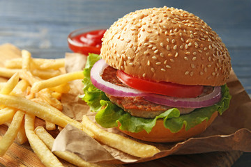 Tasty burger with french fries on cutting board