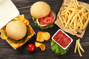 Tasty burger with french fries and chips on table