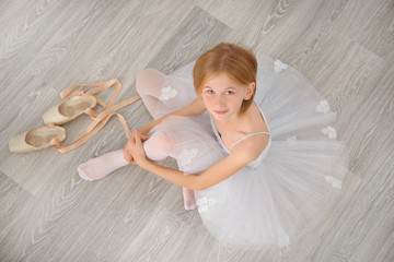 Obraz premium Small ballerina dancer sitting on floor