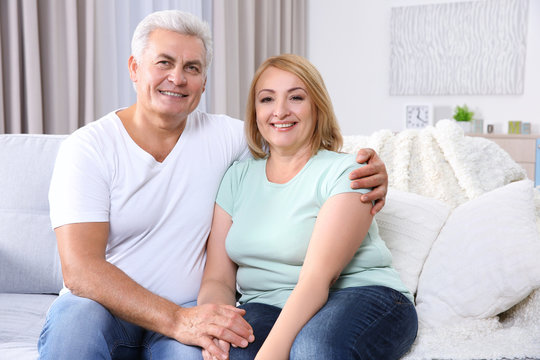 Happy grandparents sitting at home in living room