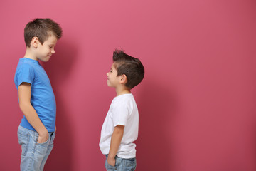 Cute little brothers standing on pink background