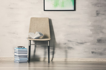 Chair with books on gray wall background