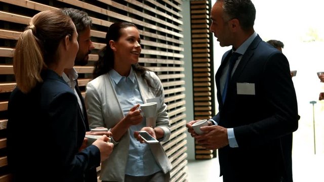 Business people interacting with each other while having cup of tea in office 4k