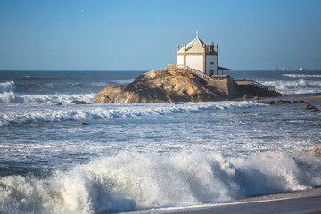 Ocean surf and Chapel Senhor da Pedra at Miramar Beach, near Porto, Portugal.