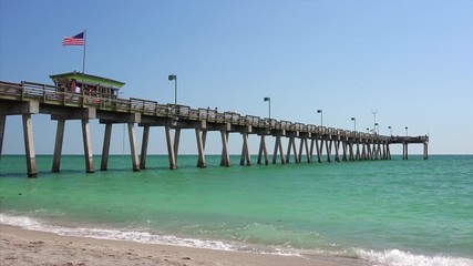 Fishing pier sticks out over the pacific ocean at beach in Venice, Florida - Powered by Adobe