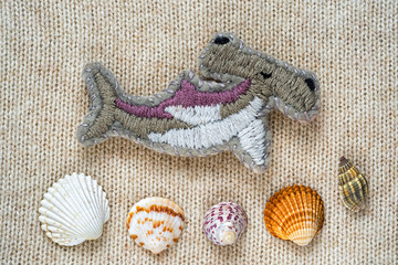 hand embroidered brooch in the form of a hammer fish and sea shells on a crafts knitting background