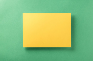Yellow blank sheet of paper light green background