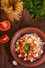 Penne pasta in tomato sauce with chicken, tomatoes decorated with parsley.