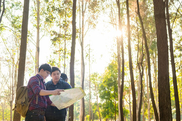 Hiking couple looking at map hiking in forest. Young interracial