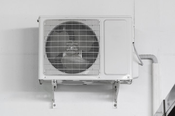 Air conditioner compressor unit on white wall.