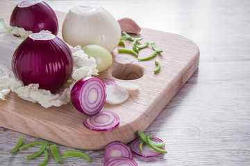 Obraz na płótnie Canvas Purple and white onions, garlic and leek on the wooden board in the kitchen. Healthy eating and lifestyle.