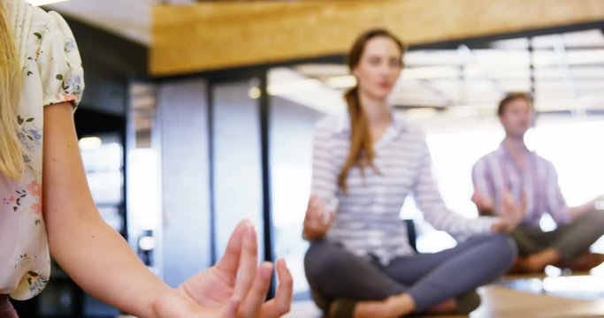 Business people performing yoga on table in office 4k