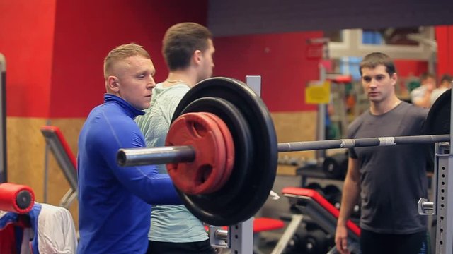 A male muscular athlete performing pull ups with heavy weights on his feet. Paurlifting. The man lifts weight. The man in the gym lifts weights. Trainings. The man carries out exercises