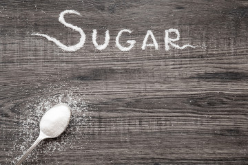 Word sugar created from sugar on the wooden background in the kitchen. Sweet meal.