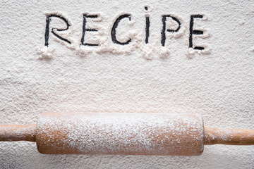 Word recipe in the white flour on the table. Healthy eating and lifestyle.