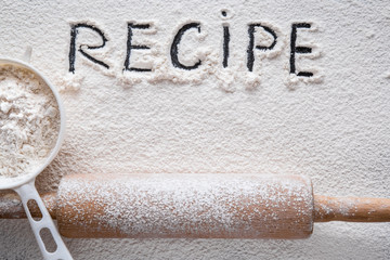 Word recipe in the white flour on the table. Healthy eating and lifestyle.