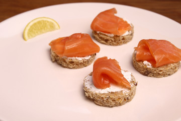 Mini sandwiches with salmon and lemon on a white plate rural food