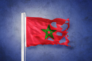 Torn flag of Morocco flying against grunge background