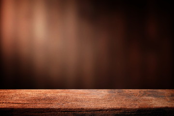 Old wood table with dark brown wall blurred background.