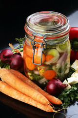 Jar with variety of pickled vegetables. Carrots, field garlic, p